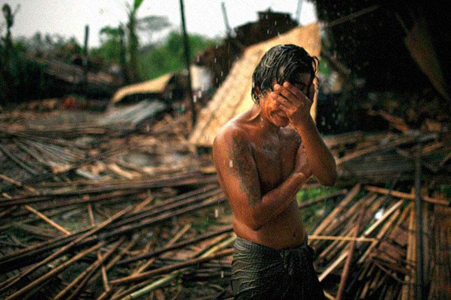 8. A man holds his face in front of what's left from his house after the cyclone Nargis